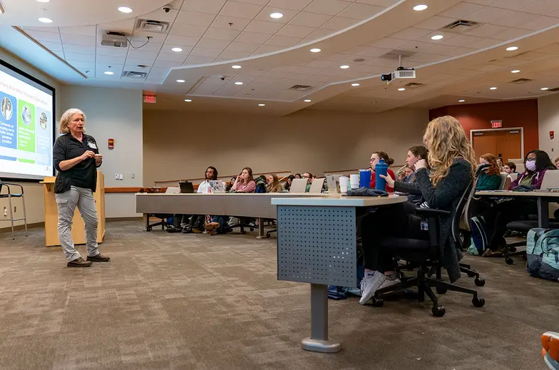 A veterinarian teaches a large room of students the specialties of community animal medicine