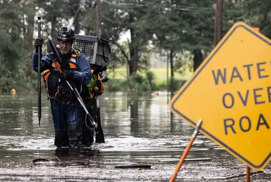 animal rescue in full gear wade through high water after a hurricane